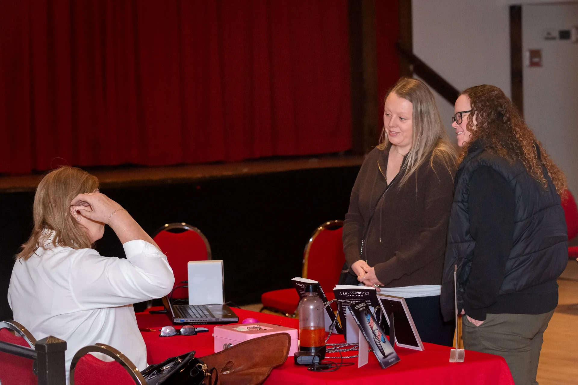 Janet chatting with two readers near the stage