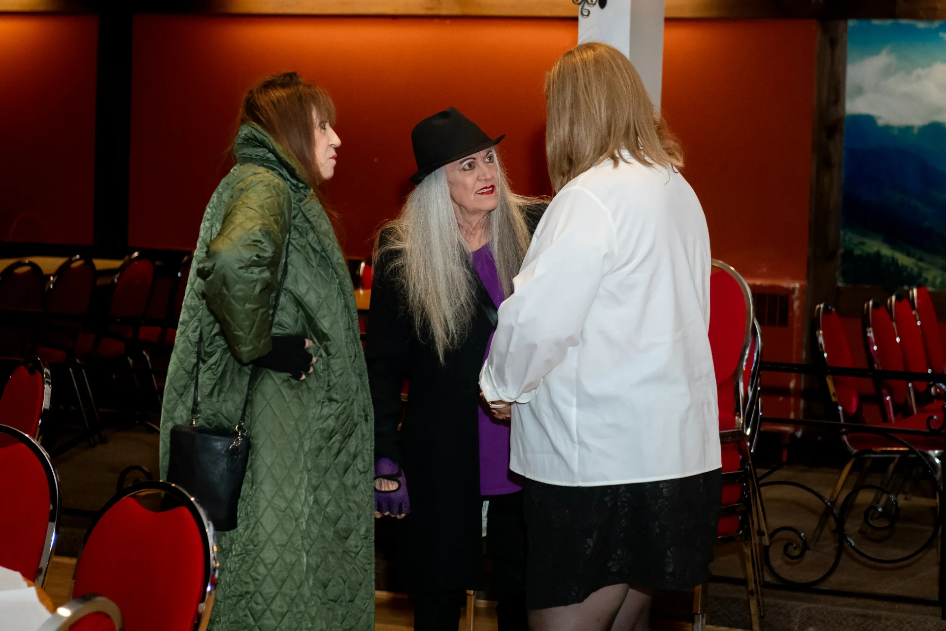 Janet in conversation with two guests near the mural