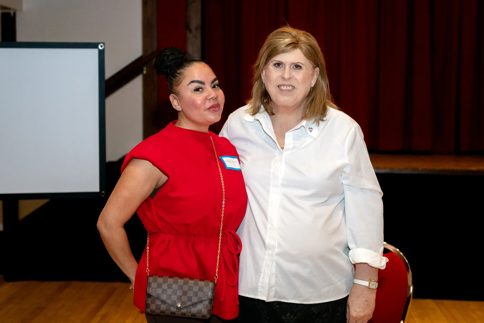 Janet posing with a guest in front of the stage