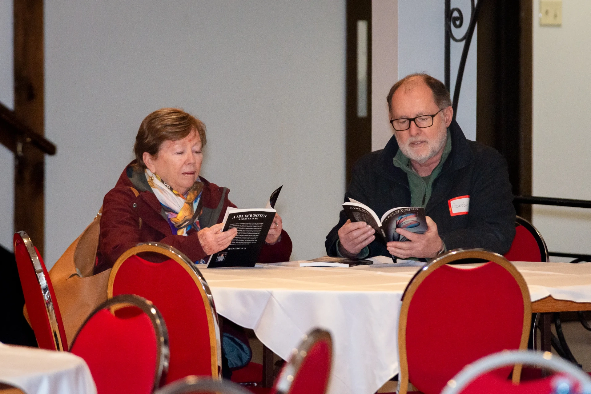 A couple reading A Life Rewritten at a table